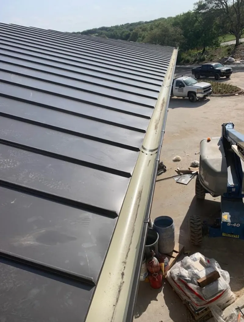 Standing seam panel and gutter detail on a metal roofing jobsite in Artesia